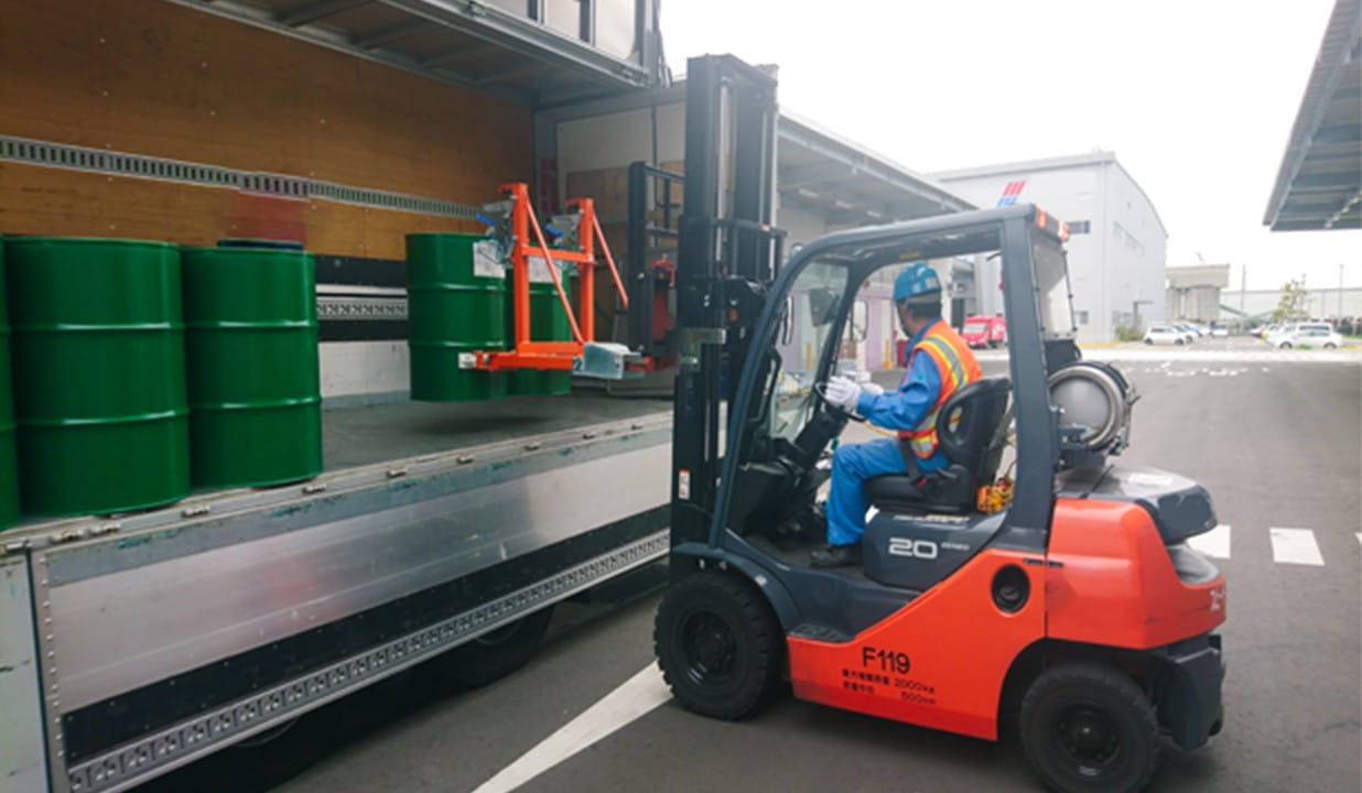 フォークリフトで荷物をトラックの荷台に乗せている作業員2人