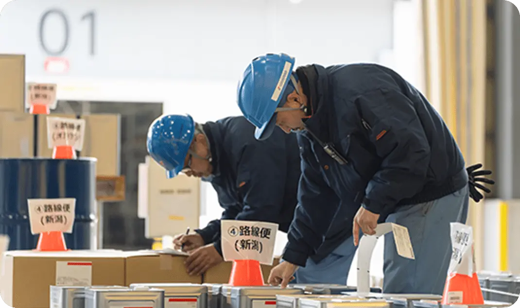 荷を確認するヘルメットを着用した物流オペレーションスタッフ2名