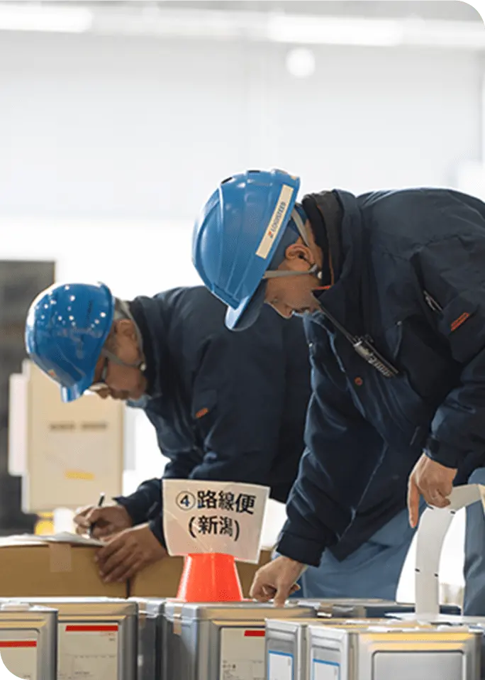 荷を確認するヘルメットを着用した物流オペレーションスタッフ2名