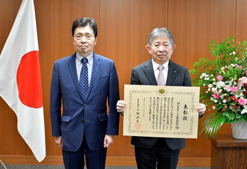 Photo of the Award Ceremony (From left) Mr. Satoru Mizushima, Vice-Minister for Transport and Tourism,   Mr. Ryōichi Okamoto, General Manager, Safety and Quality Control Management Office of LOGISTEED, Ltd. 