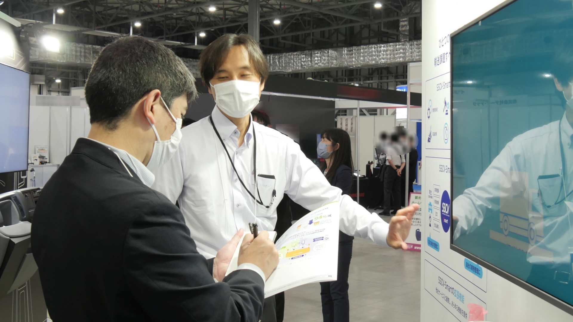 筆者（左）に説明する日立物流 輸送事業強化PJ SSCV強化グループ 担当部長 浦瀬大河氏（右）